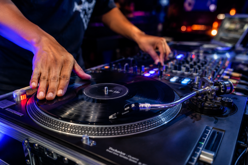 DJ scratching a professional turntable during a live music performance with colorful nightclub lighting and energetic party atmosphere